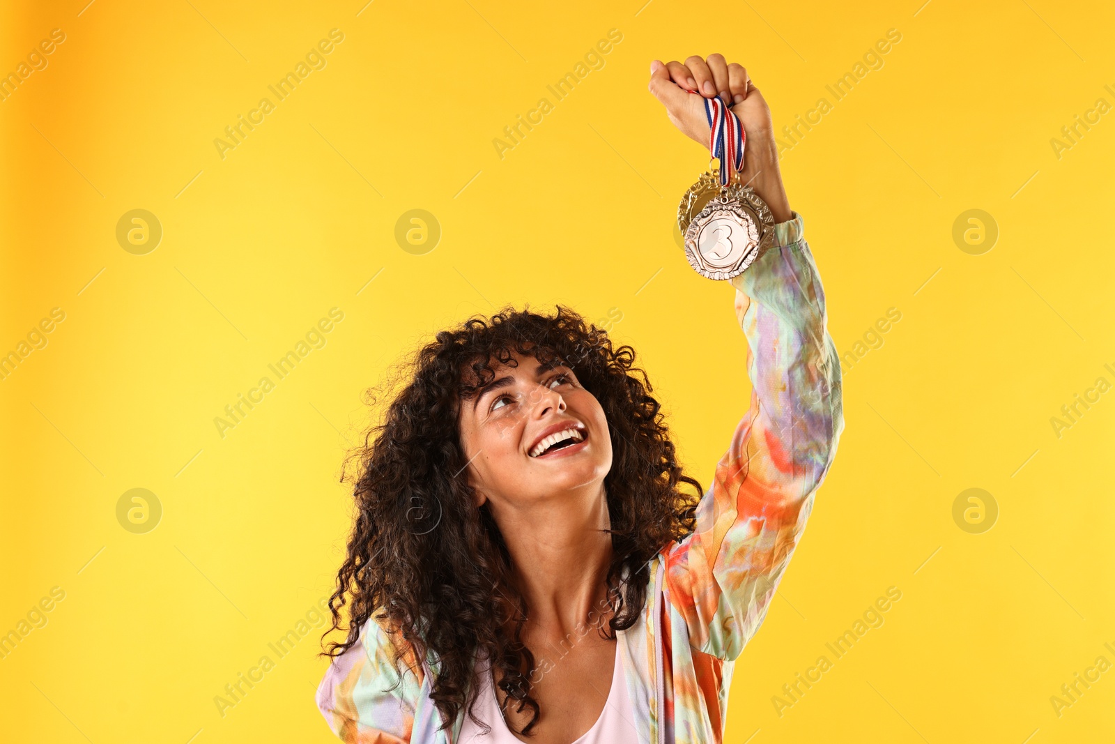 Photo of Happy winner showing different medals on yellow background