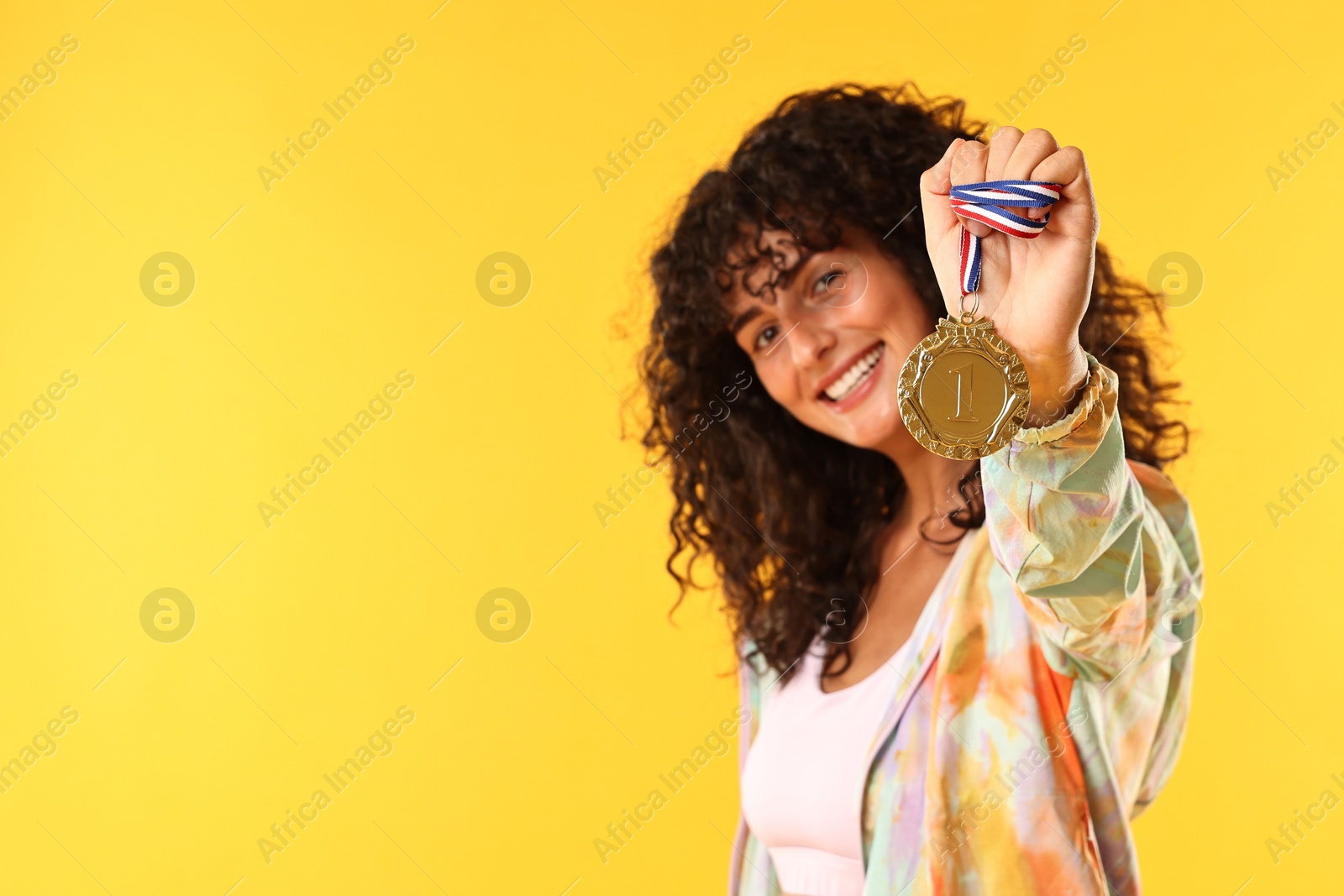 Photo of Happy winner with golden medal on yellow background. Space for text