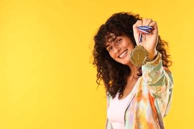 Photo of Happy winner with golden medal on yellow background. Space for text