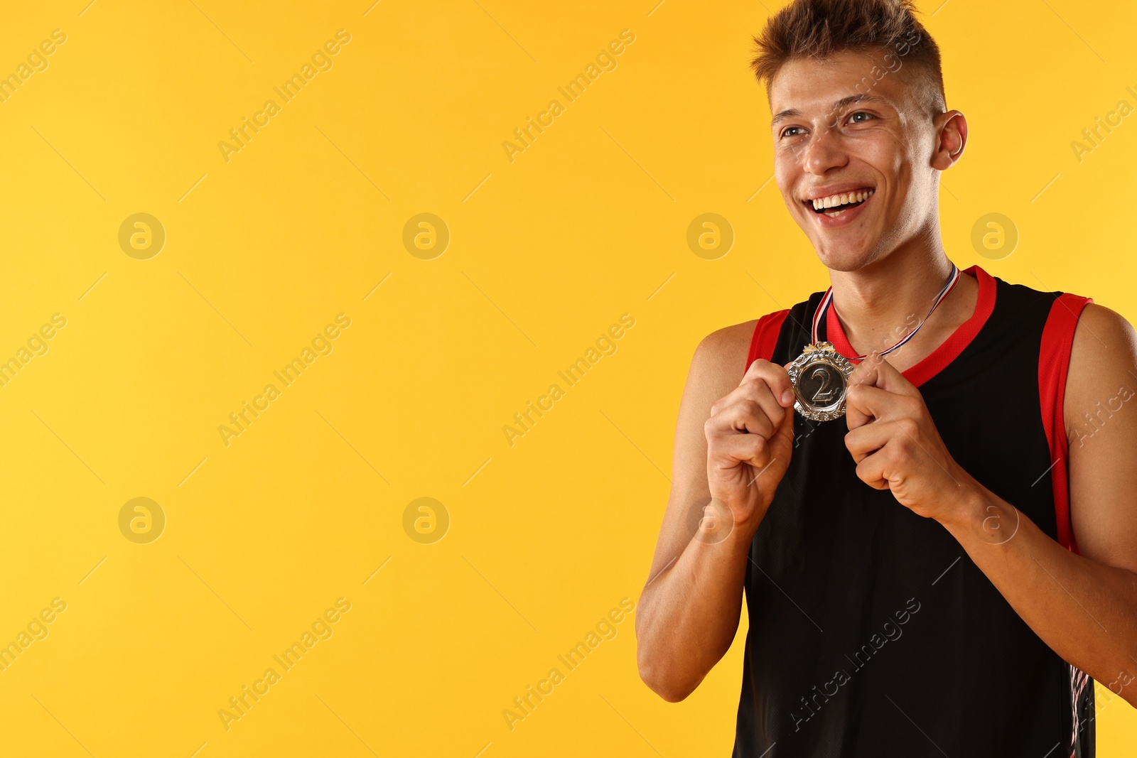 Photo of Happy winner with silver medal on yellow background. Space for text