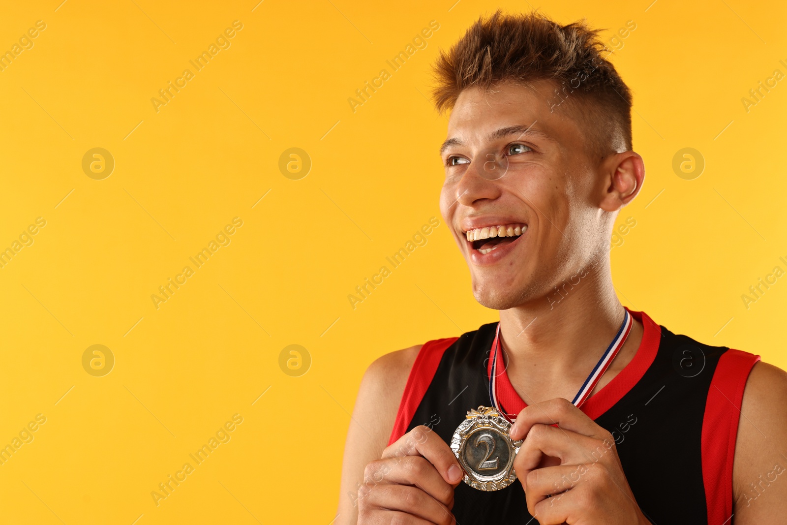 Photo of Happy winner with silver medal on yellow background. Space for text