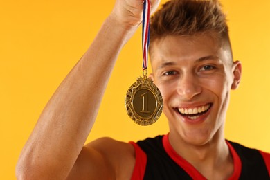 Photo of Happy winner with golden medal on yellow background, selective focus