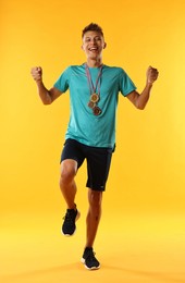 Photo of Happy winner with different medals on yellow background