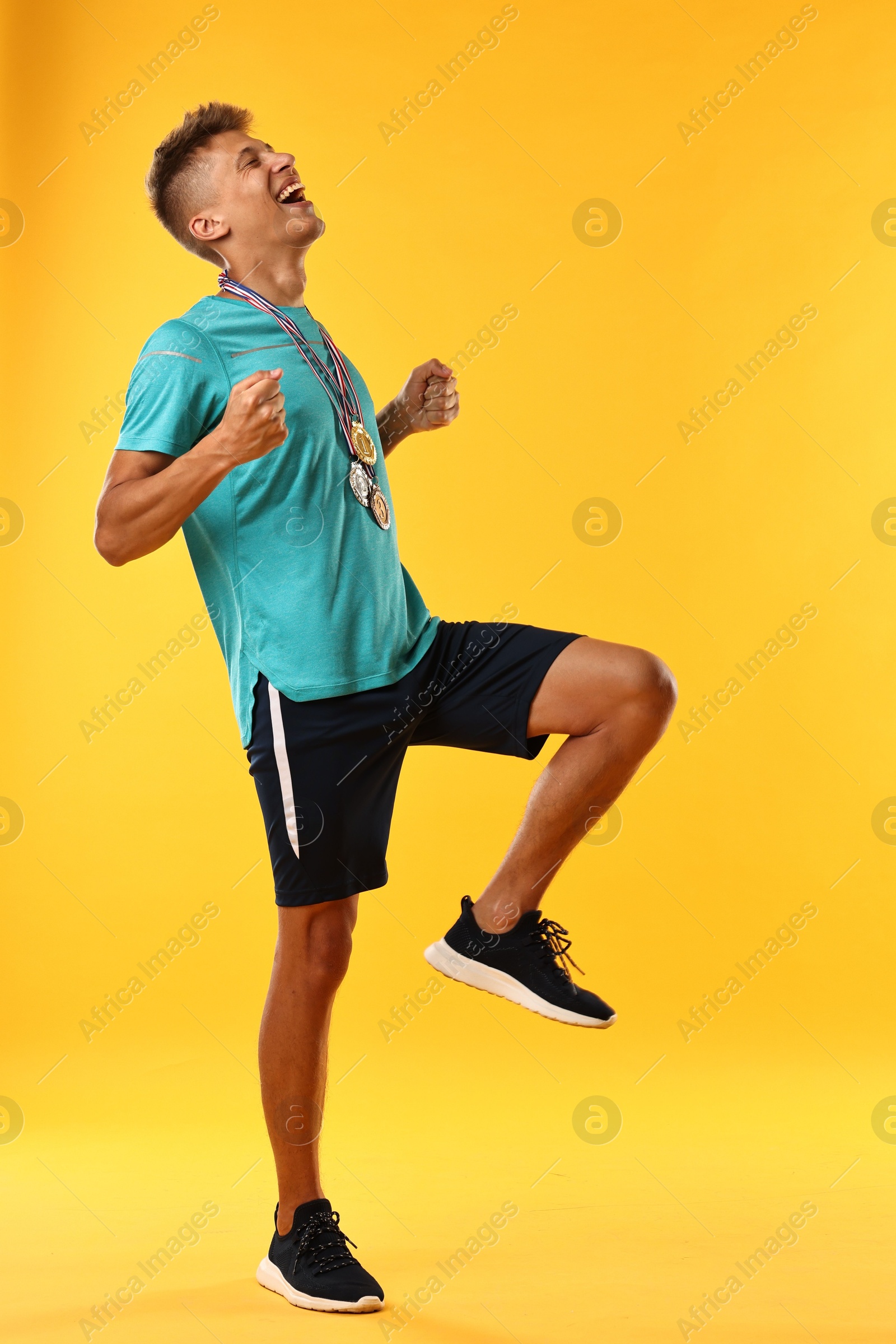 Photo of Happy winner with different medals on yellow background