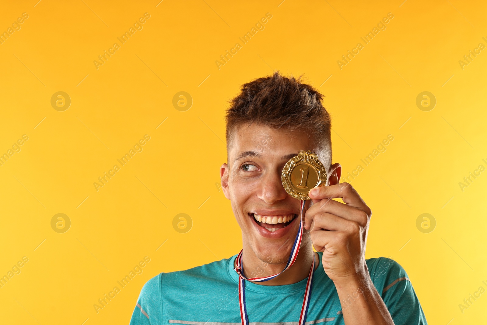 Photo of Happy winner with golden medal on yellow background. Space for text