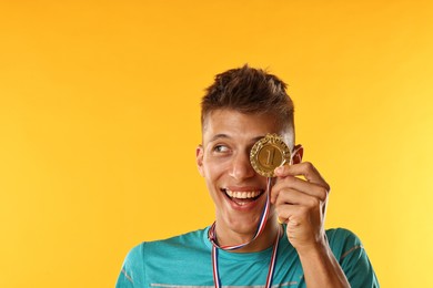 Photo of Happy winner with golden medal on yellow background. Space for text