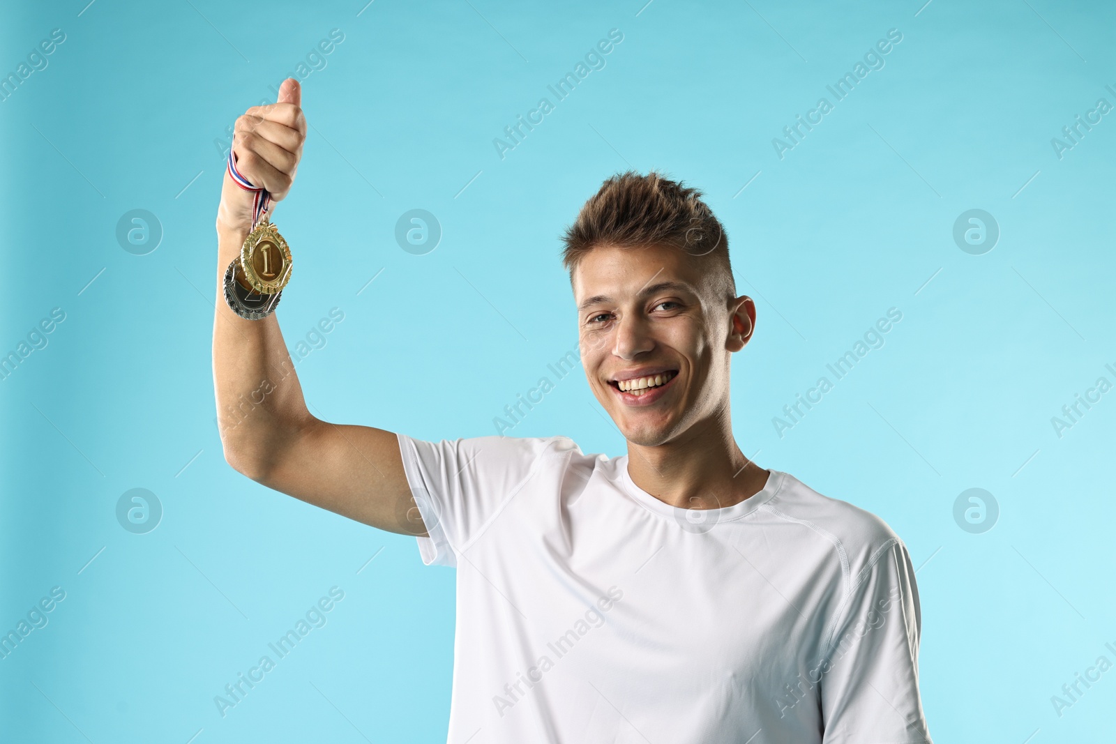 Photo of Happy winner with different medals on light blue background