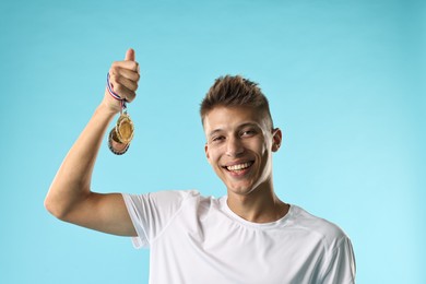 Photo of Happy winner with different medals on light blue background