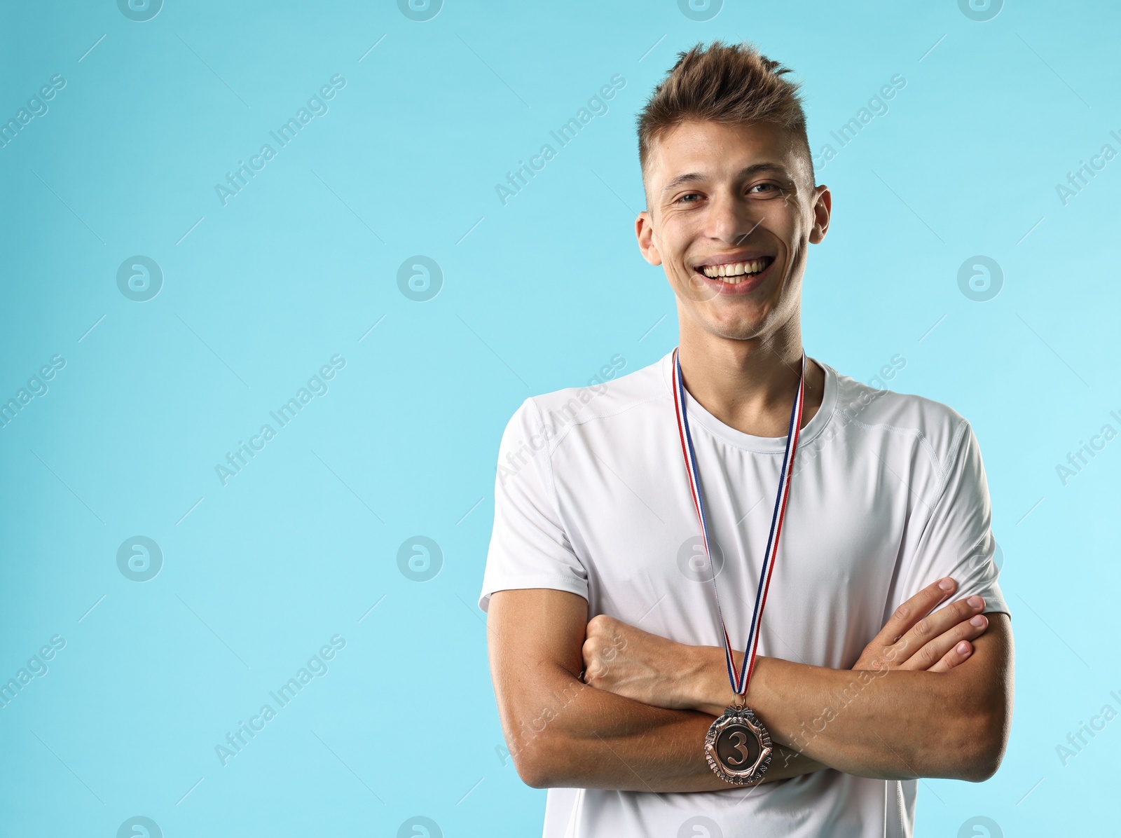 Photo of Happy winner with bronze medal on light blue background. Space for text