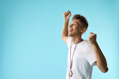 Photo of Happy winner with bronze medal on light blue background. Space for text