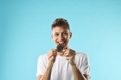 Photo of Happy winner with bronze medal on light blue background