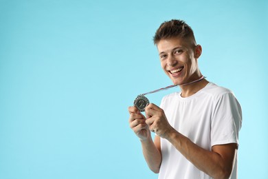 Photo of Happy winner with silver medal on light blue background. Space for text