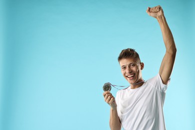 Photo of Happy winner with silver medal on light blue background. Space for text