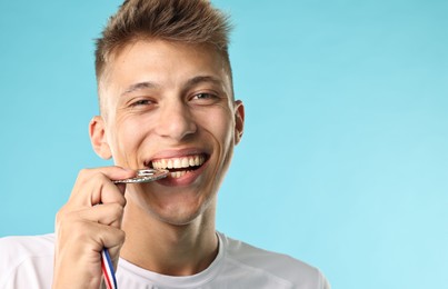 Happy winner with silver medal on light blue background, closeup. Space for text