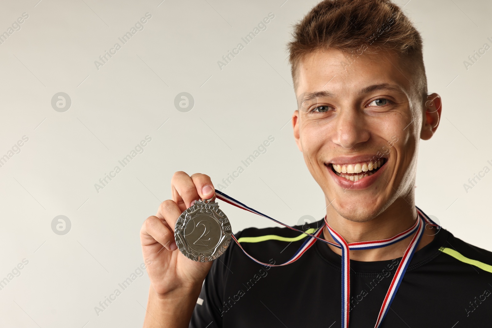 Photo of Happy winner with silver medal on light grey background. Space for text