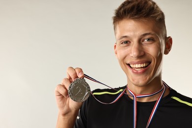 Photo of Happy winner with silver medal on light grey background. Space for text