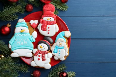 Photo of Delicious cookies in shape of snowmen and Christmas decor on blue wooden table, flat lay. Space for text