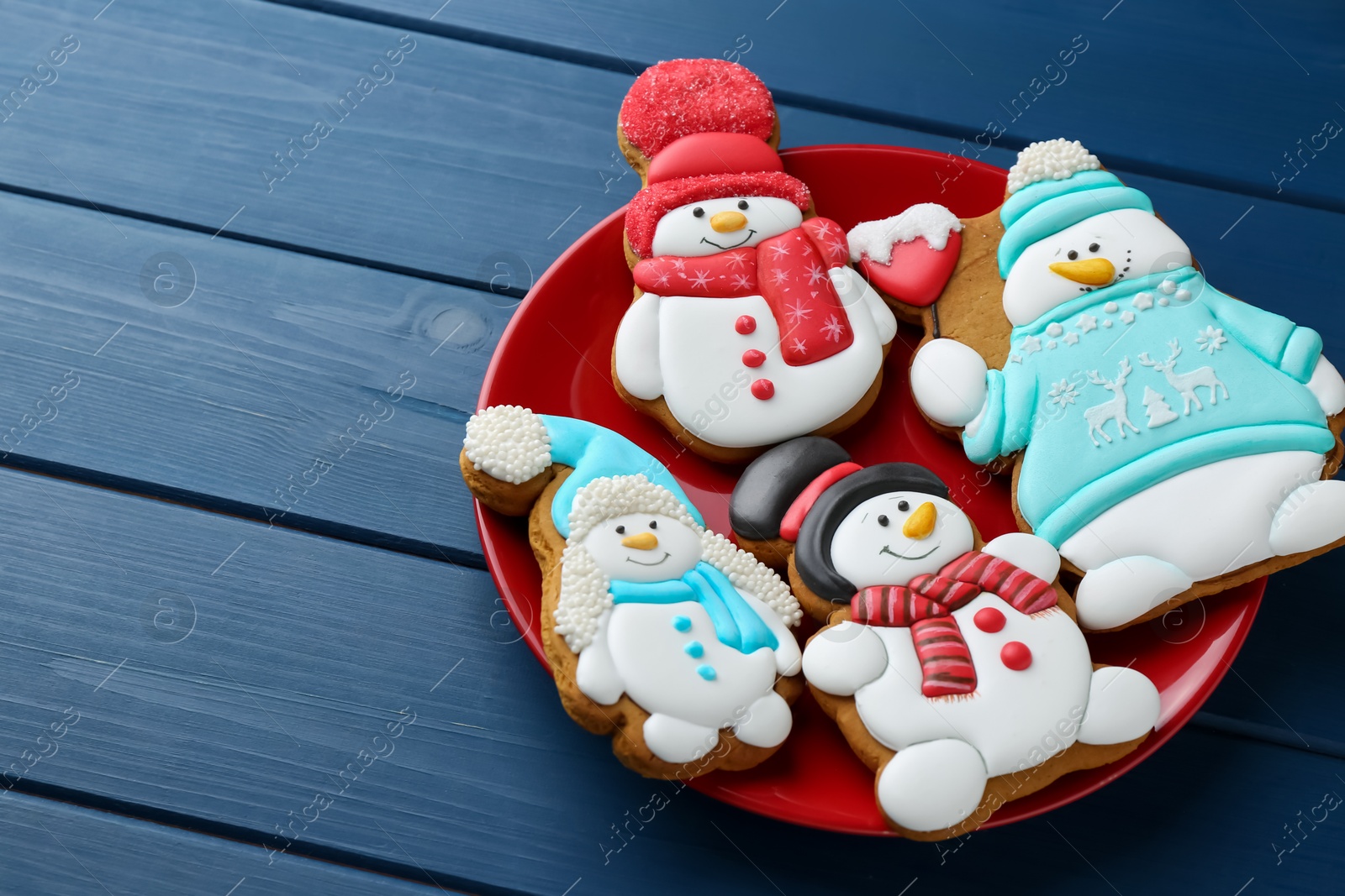 Photo of Delicious cookies in shape of snowmen on blue wooden table, closeup