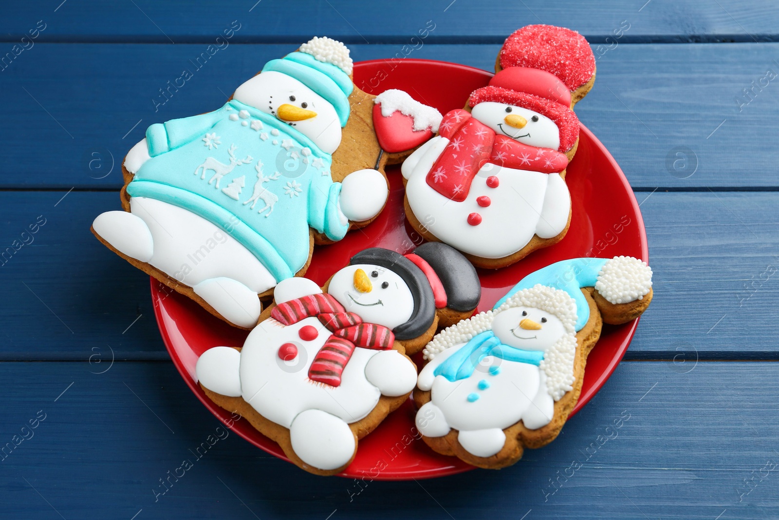 Photo of Delicious cookies in shape of snowmen on blue wooden table, closeup