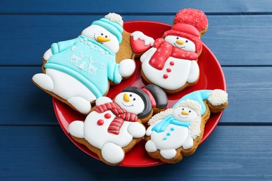 Photo of Delicious cookies in shape of snowmen on blue wooden table, closeup