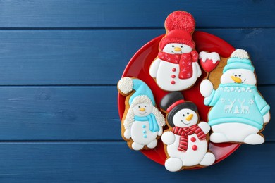 Photo of Delicious cookies in shape of snowmen on blue wooden table, top view. Space for text