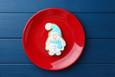 Photo of Delicious cookie in shape of snowman on blue wooden table, top view