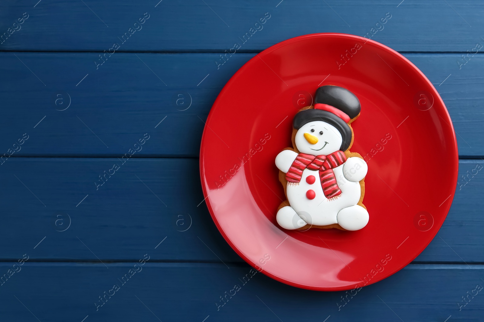 Photo of Delicious cookie in shape of snowman on blue wooden table, top view. Space for text