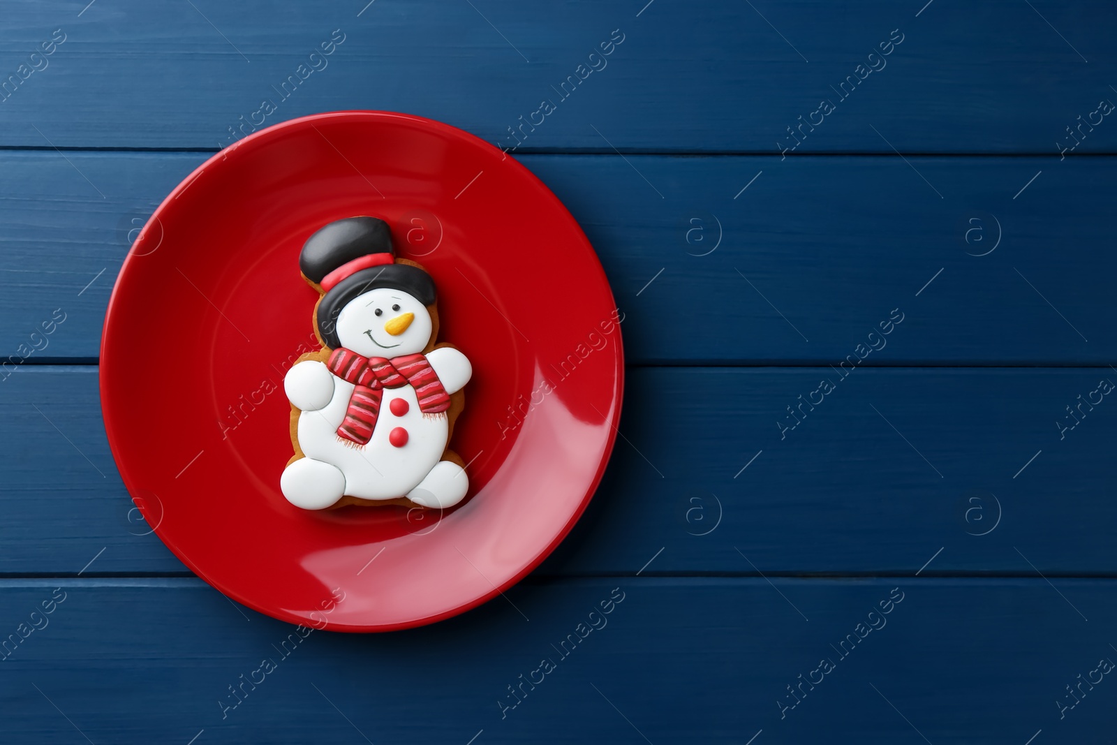 Photo of Delicious cookie in shape of snowman on blue wooden table, top view. Space for text