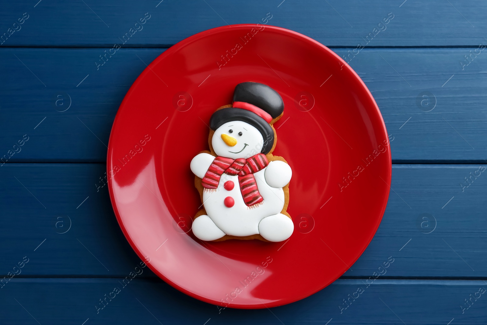 Photo of Delicious cookie in shape of snowman on blue wooden table, top view