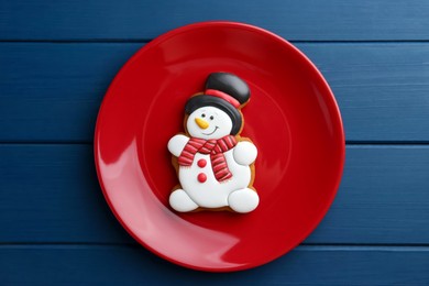 Photo of Delicious cookie in shape of snowman on blue wooden table, top view