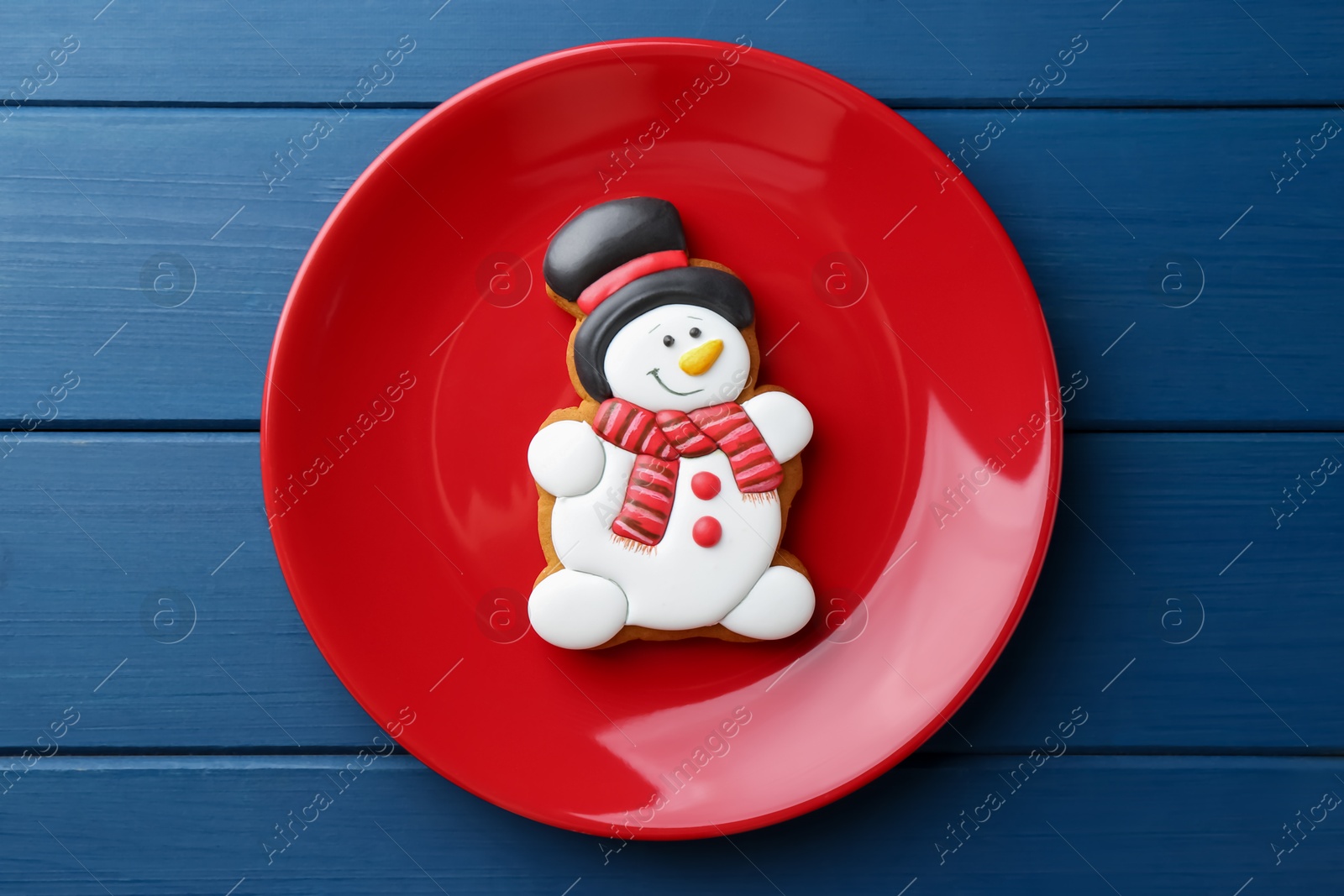 Photo of Delicious cookie in shape of snowman on blue wooden table, top view