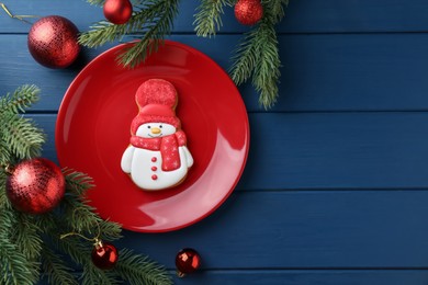 Photo of Delicious cookie in shape of snowman and Christmas decor on blue wooden table, flat lay. Space for text