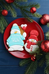 Photo of Delicious cookies in shape of snowmen and Christmas decor on blue wooden table, flat lay