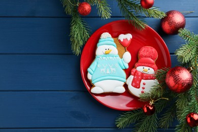 Photo of Delicious cookies in shape of snowmen and Christmas decor on blue wooden table, flat lay. Space for text