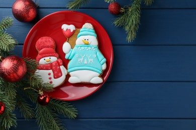 Photo of Delicious cookies in shape of snowmen and Christmas decor on blue wooden table, flat lay. Space for text