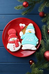 Photo of Delicious cookies in shape of snowmen and Christmas decor on blue wooden table, flat lay