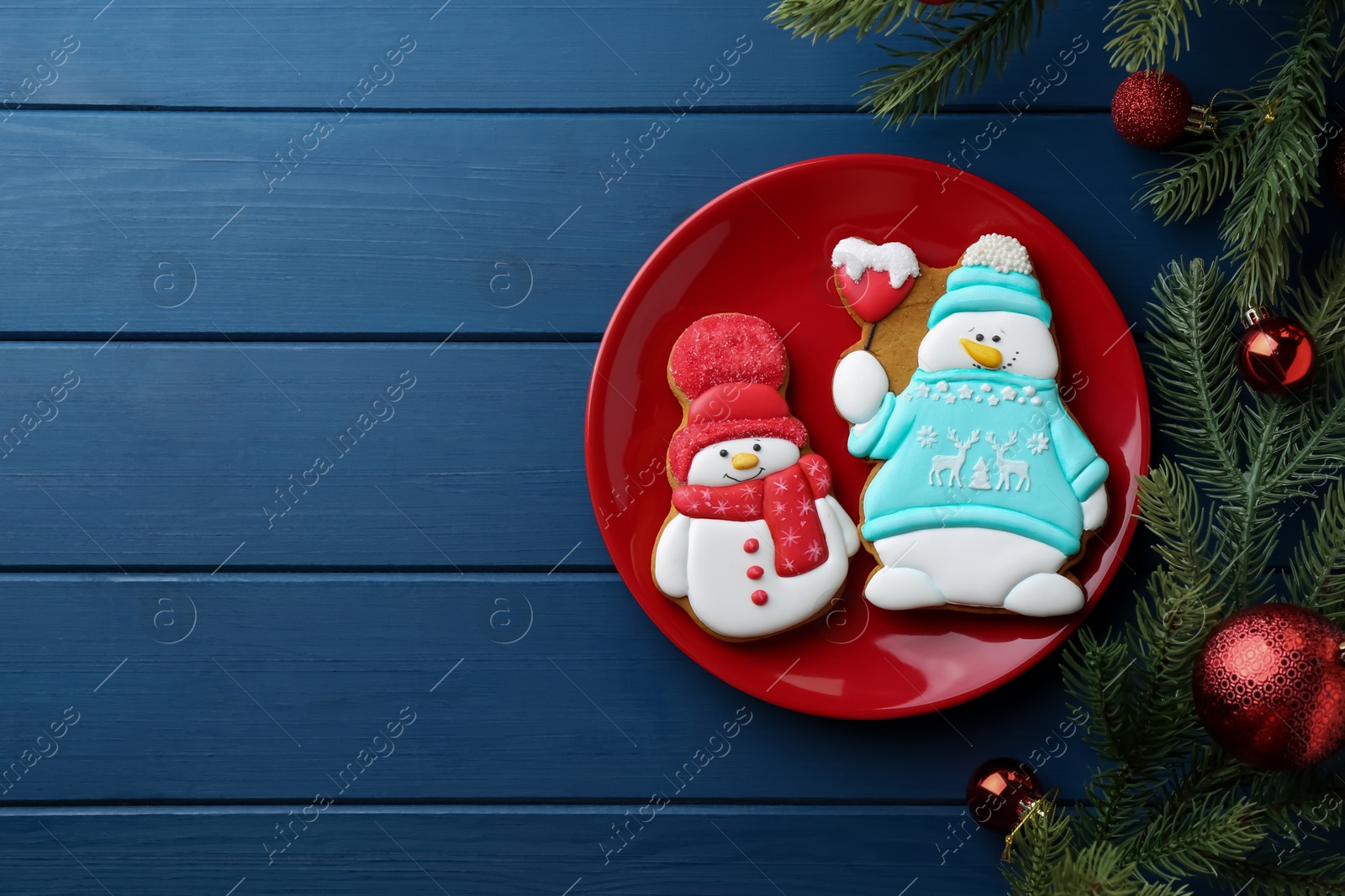 Photo of Delicious cookies in shape of snowmen and Christmas decor on blue wooden table, flat lay. Space for text