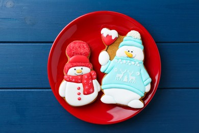 Photo of Delicious cookies in shape of snowmen on blue wooden table, top view