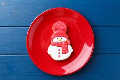 Photo of Delicious cookie in shape of snowman on blue wooden table, top view