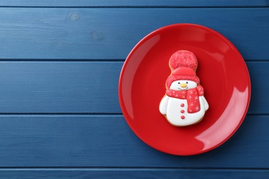 Photo of Delicious cookie in shape of snowman on blue wooden table, top view. Space for text