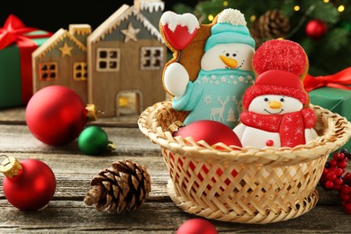 Photo of Delicious cookies in shape of snowmen and Christmas decor on wooden table