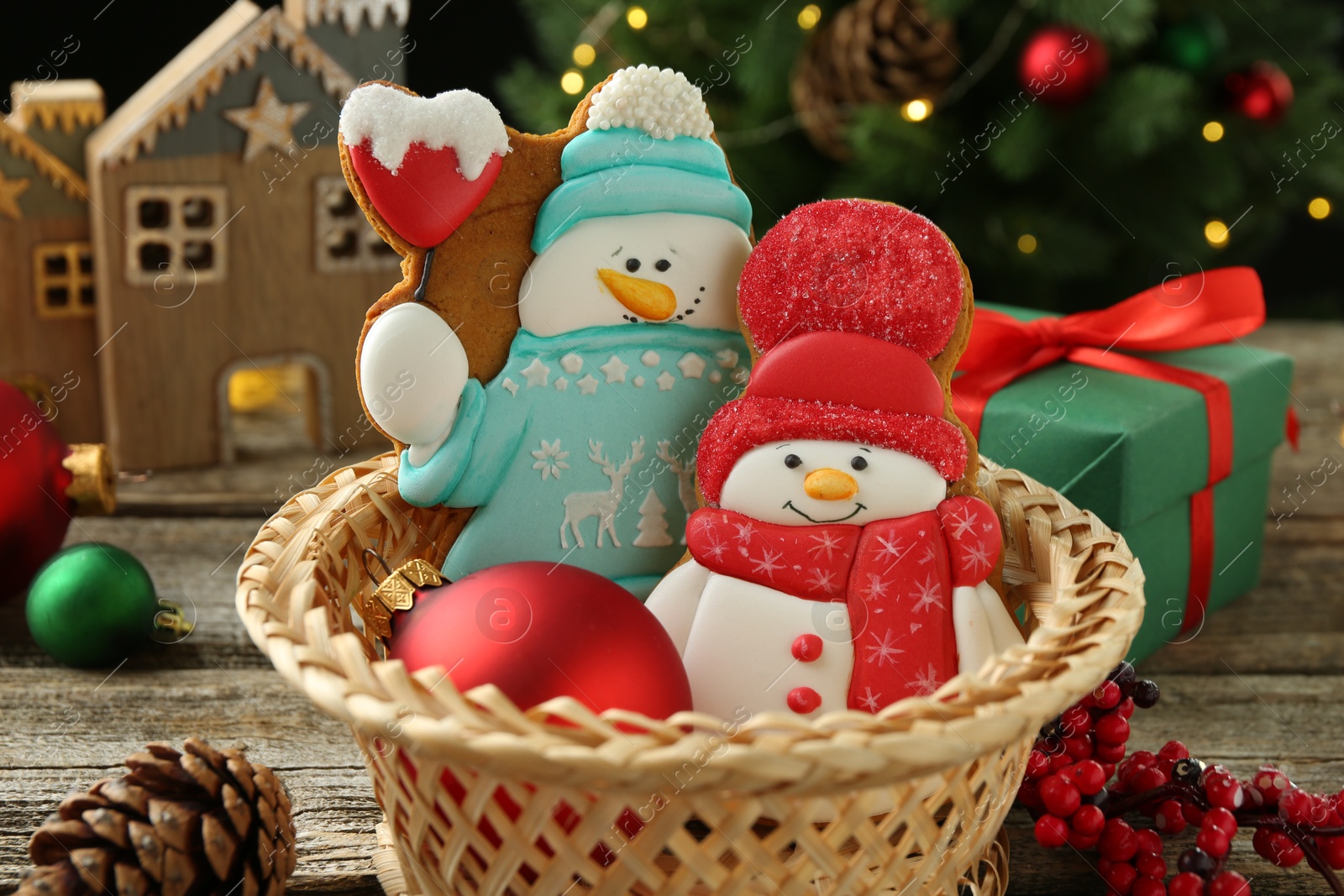 Photo of Delicious cookies in shape of snowmen and Christmas decor on wooden table, closeup