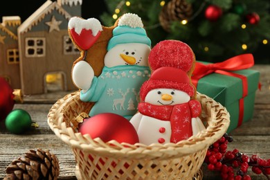 Photo of Delicious cookies in shape of snowmen and Christmas decor on wooden table, closeup