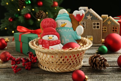 Photo of Delicious cookies in shape of snowmen and Christmas decor on wooden table