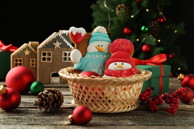 Photo of Delicious cookies in shape of snowmen and Christmas decor on wooden table