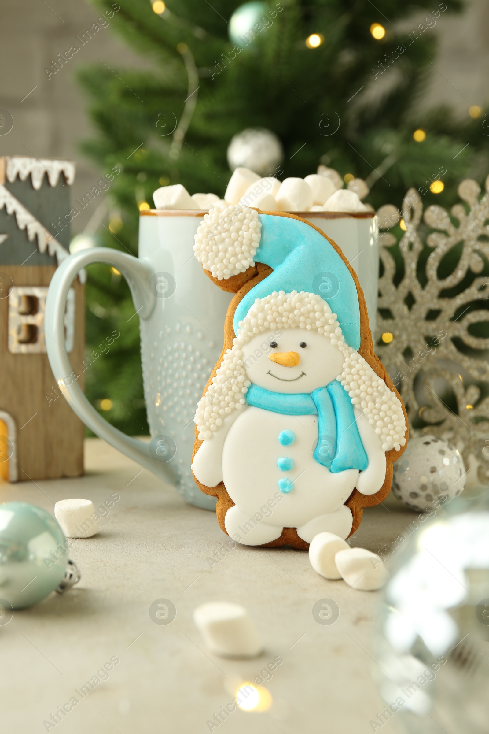 Photo of Delicious cookie in shape of snowman, cup with cocoa and Christmas decor on light grey table