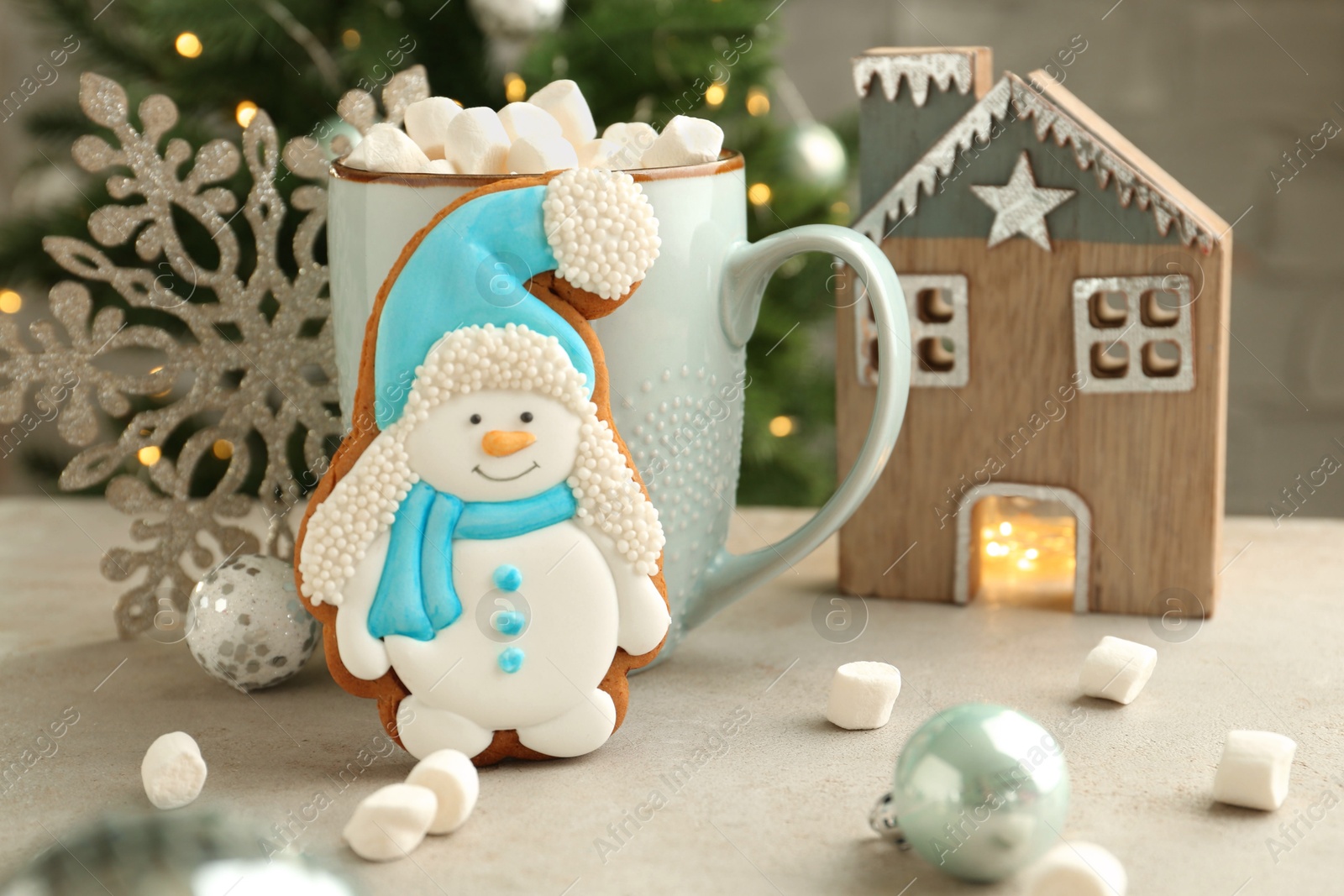 Photo of Delicious cookie in shape of snowman, cup with cocoa and Christmas decor on light grey table, closeup