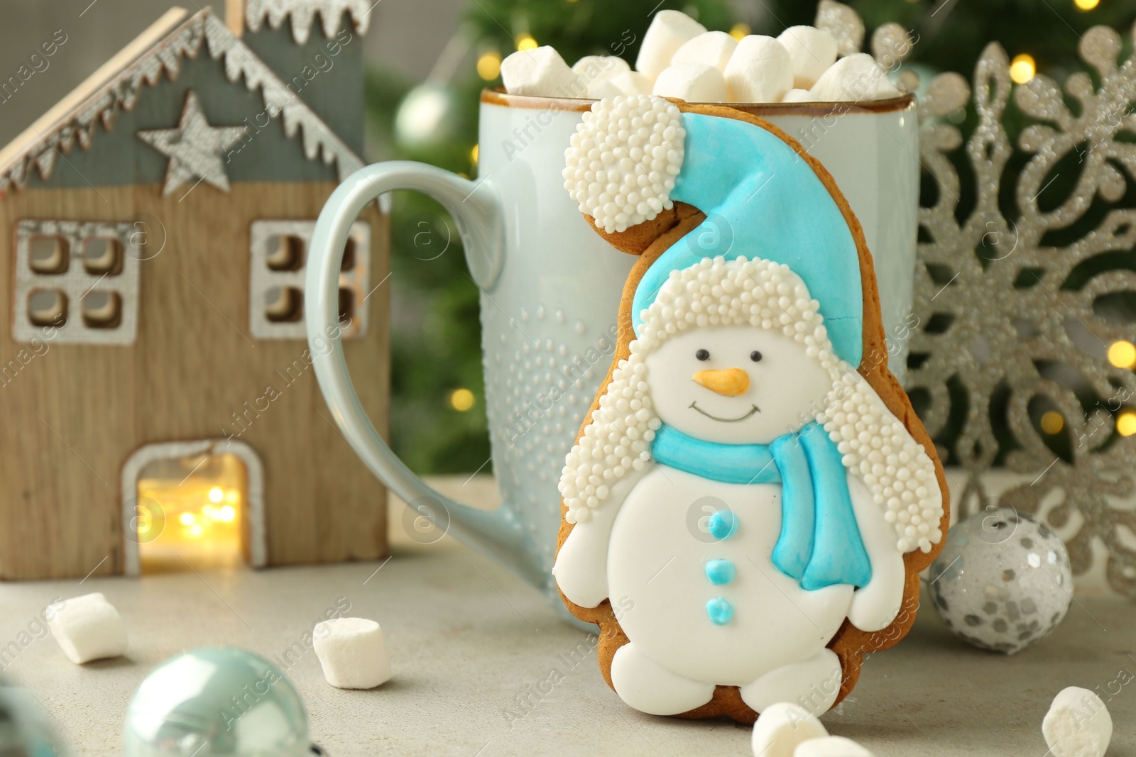 Photo of Delicious cookie in shape of snowman, cup with cocoa and Christmas decor on light grey table, closeup