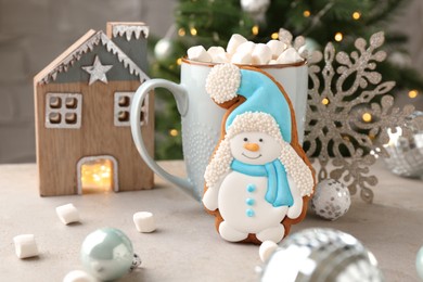 Photo of Delicious cookie in shape of snowman, cup with cocoa and Christmas decor on light grey table