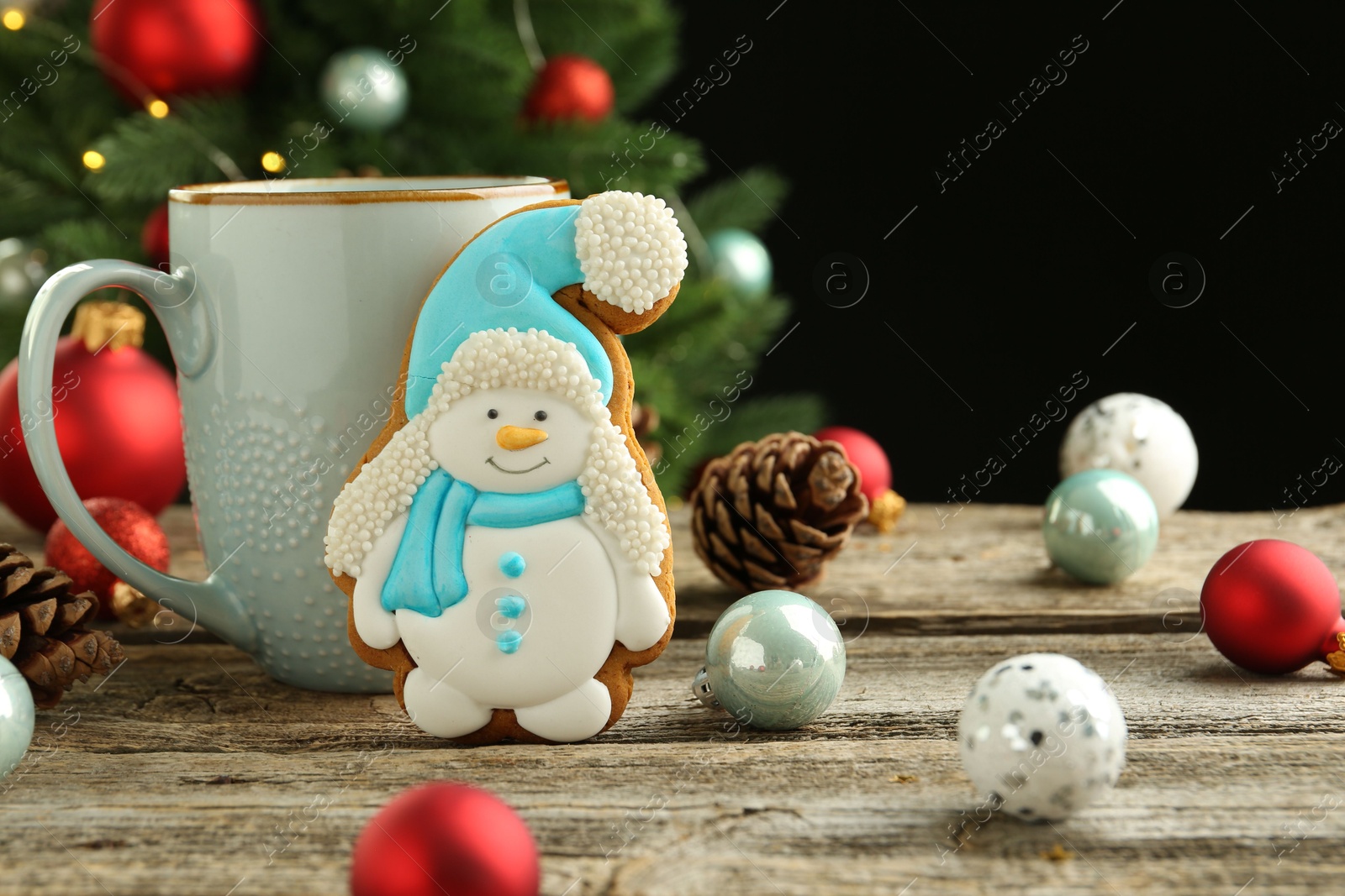 Photo of Delicious cookie in shape of snowman, cup with cocoa and Christmas decor on wooden table